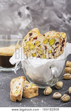 Crispy traditional delicious Italian biscotti cookies or kantuchchi with pistachios and dried cranberries in a glass on a marble background. selective focus