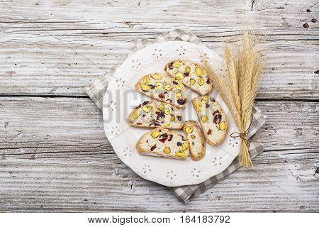 Crispy traditional delicious Italian biscotti cookies or kantuchchi with pistachios and dried cranberries in a glass on wooden background. selective