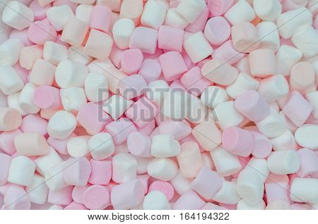 Colorful mini marshmallows background close-up texture. A pile of different mini white pink and orange puffy marshmallows. Marshmallow concept. Wallpaper for desktop. Top view.
