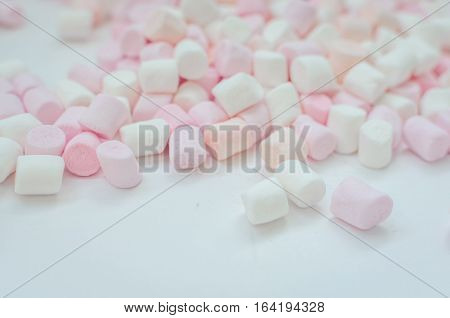 Colorful mini marshmallows background close-up texture. A pile of different mini white pink and orange puffy marshmallows. Marshmallow concept. Wallpaper for desktop. Selective focus.