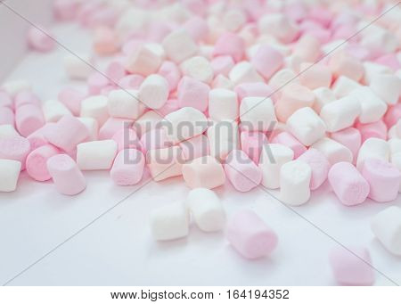 Colorful mini marshmallows background close-up texture. A pile of different mini white pink and orange puffy marshmallows. Marshmallow concept. Wallpaper for desktop. Selective focus.
