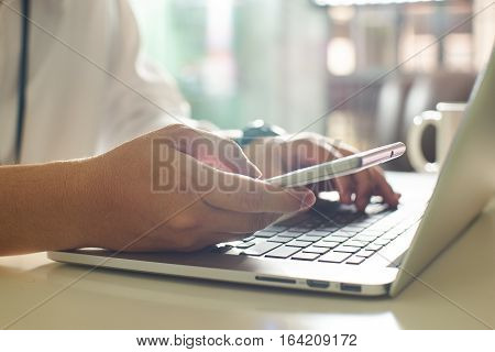 businessman hand using smart phone and keying the data to laptopclose up Seleted focus.