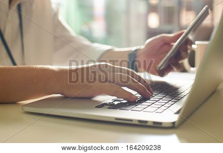 businessman hand using smart phone and keying the data to laptopclose up Seleted focus.