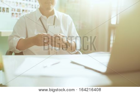 Businessman hand using smart phone in front of laptop and table .Seleted focus.