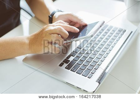 Young man hand using smart phone and laptopclose up Seleted focus.