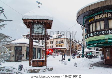 Chamonix, France - January 30, 2015: Street view with clock, cafe and central square in Chamonix, one of the oldest ski resorts in French Alps