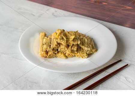 Tofu skin (yuba sticks or Fuzhu) and chopsticks on a concrete table. Healthy asian soy food
