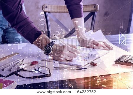 Man doing paperwork at workplace with abstract city. Double exposure