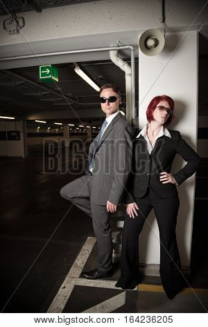 mafiosi couple posing in a parking garage
