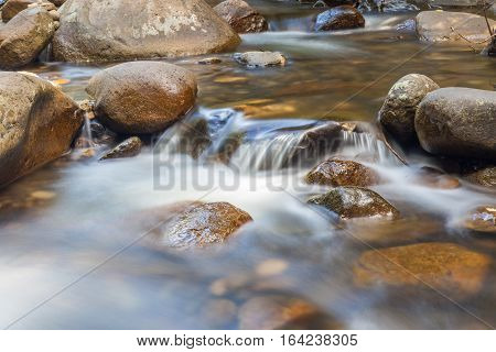 Clear water of stream flowing through natural mountain rocks.
