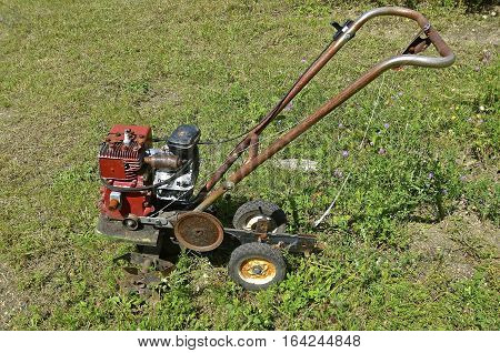 An old rusty garden tiller is ready for usage or to be sent to the junkyard for salvage,parets, or scrap metal