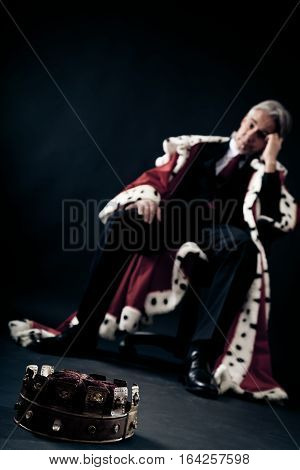 businessman in king's clothes lost it and looks quite depressed