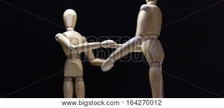 Wooden Mannequins-shaking-focusBlur - Two wooden mannequin's shaking hands. Shot close in with focus blur and from behind the right mannequin.