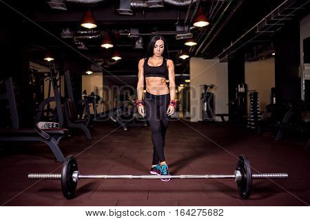 Muscular young fitness woman preparing for heavy deadlift exercise in gym