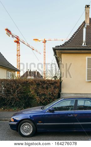 STRASBOURG FRANCE - NOV 29 2016: Blue BMW luxury limousine sedan parked in city with luxury real estate building in the background and cranes working in the background