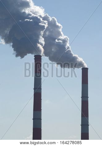 Two industrial long smoke pipes and lot of white steam