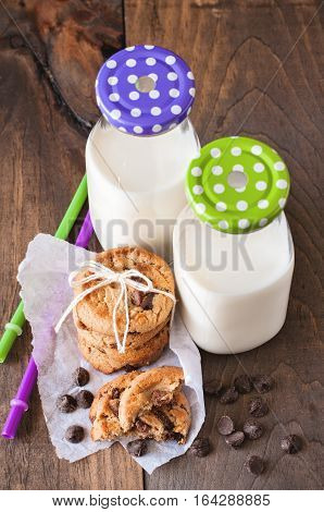 Milk bottles and chocolate chips cookies. Toned image. Selective focus on cookies.
