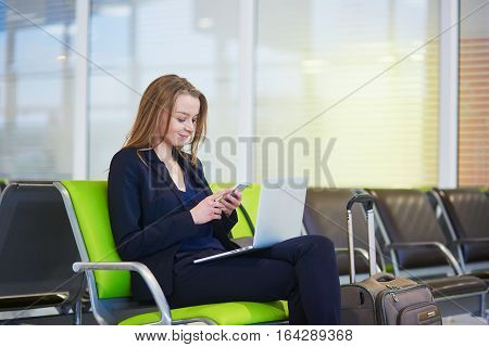 Woman In International Airport Terminal, Checking Her Phone