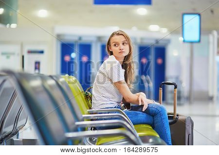 Tourist Girl In International Airport, Waiting For Her Flight, Looking Upset