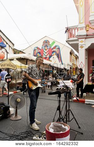 PHUKET THAILAND SEPTEMBER 27: Street artist musician entertains tourists at the walking street among old building Chino Portuguese style on street of Phuket town Thailand on September 27 2016.