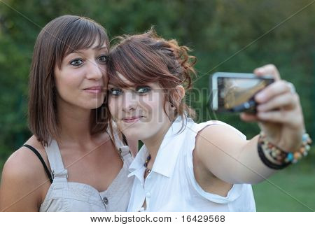 dois jovens caucasianas amigas tirar auto-retratos de si se divertindo ao ar livre em um