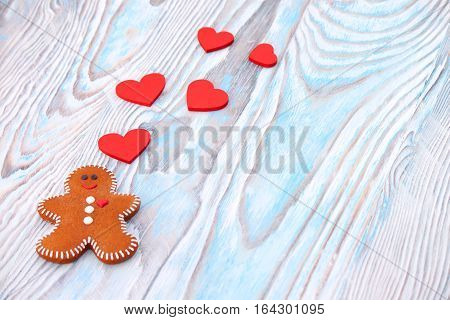 card for St. Valentine's Day gingerbread man with red hearts on a light soft wooden background close up with a place for the text