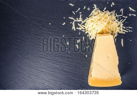 Top View Of Single Tasty Fresh Yellow Big Segment Piece Parm And Large Grated Cheese On Stone Slate