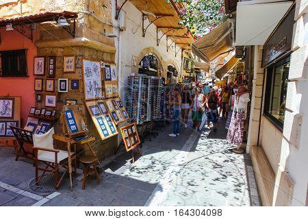 Rethymnon, Island Crete, Greece - July 1 2016: People and tourists walking on the narrow street of Rethymnon (part of Old Town) and buying souvenirs