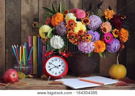 Bouquet pumpkins pencils Apple books and clock on the table. Still life. Back to school. Teacher's Day. September 1.