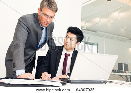 Manager and employee in office, looking at documents