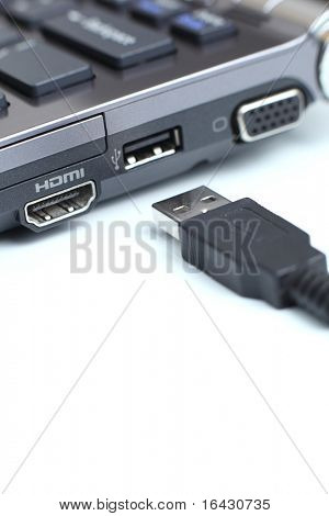 portátil de carbono moderno alta gama con gran conectividad y un cable USB sobre fondo blanco