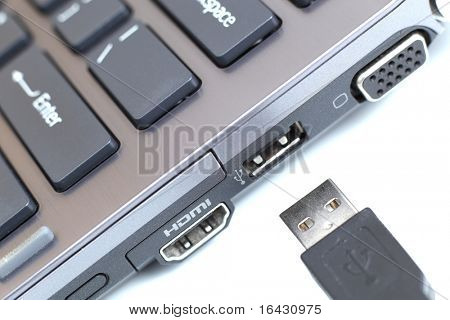 portátil de carbono moderno alta gama con gran conectividad y un cable USB sobre fondo blanco