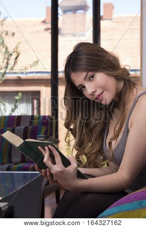 Beautiful girl reading a book in living room