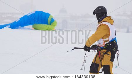 Snowkiting in the snow on frozen river, kite surfer ready for sliding, telephoto