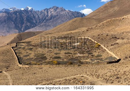 destroyed house enclosed by a stone wall in the Himalayas Nepal view from above