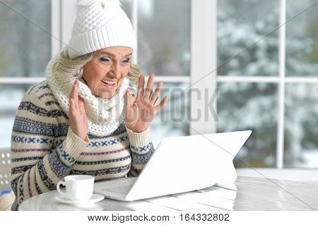 mature woman using laptop in cafe near window