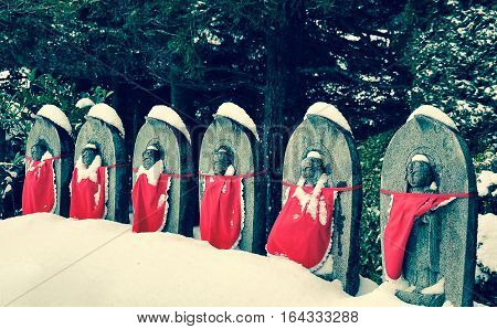 Jizo or stone statue wearing red apron under snow in vintage style Koyasan Japan