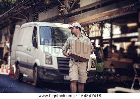 Messenger delivering parcel, walking in street next to his van
