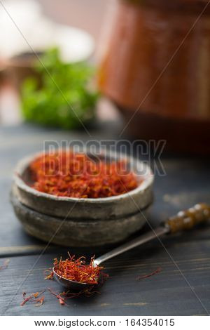 Raw Organic Red Saffron Spice in a clay bowl on wooden table