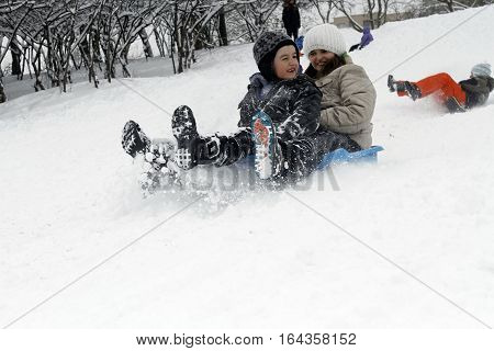 BUCHAREST ROMANIA - January 07 2017: Joyful children are sledding down the hills on a winter day in a central park during the vacation.