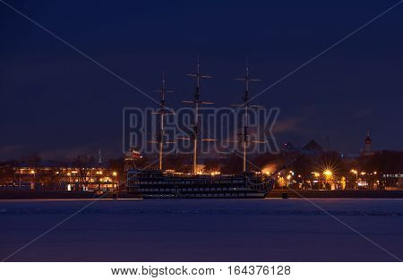 Old wooden ship near bank of Saint-Petersburg in winter night time.