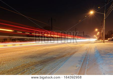 Snow covered winter road with shining streetlights in rural areas at sunset winter night snow covered roads with snow