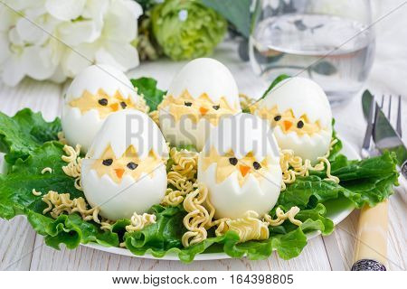 Little chicken in nest deviled eggs served with salad and dry ramen on white plate horizontal