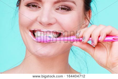 Woman brushing cleaning teeth. Girl with toothbrush close up. Oral hygiene. Blue green background