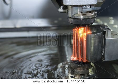 Close-up of the wire - EDM CNC machine while cutting the sample work pieces with the glowing edge lighting effect