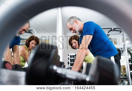 Beautiful fit senior couple in gym working out with weights