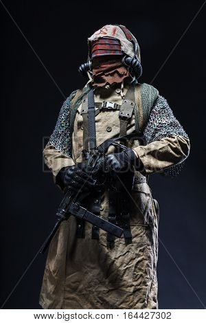 Nuclear post apocalypse life after doomsday concept. Scary closed face of survivor with homemade weapons. Studio closeup portrait on black background