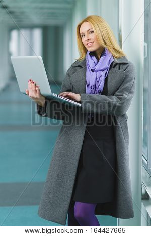 Portrait of blond businesswoman working on laptop in lobby.