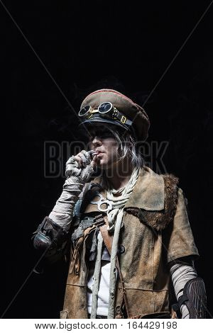 Nuclear post apocalypse life after doomsday concept. Grimy female survivor smoking. Studio closeup portrait on white background