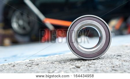Car Suspension and car bearing parts concept - New wheels car bearing on asphalt floor in garage and copyspace
